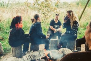 4 people gathered around a fire, deep in conversation and laughter